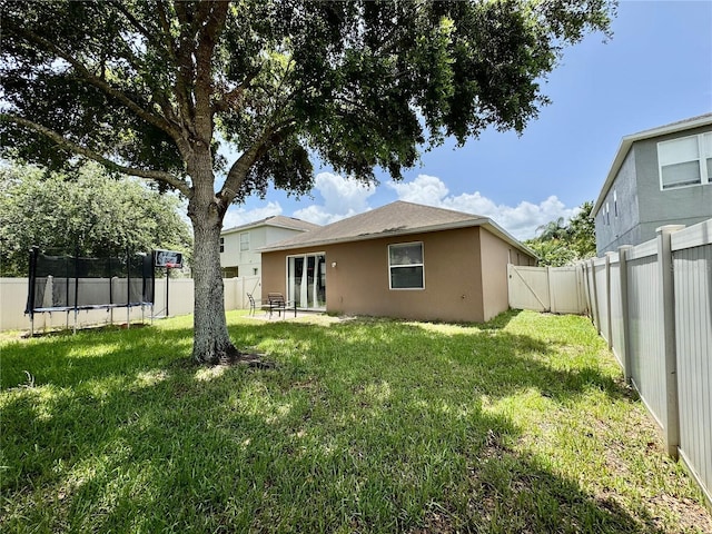 13303 Moss Park Ridge Dr, Orlando, FL 32832 - rear view of property with a trampoline, a fenced backyard, and stucco siding