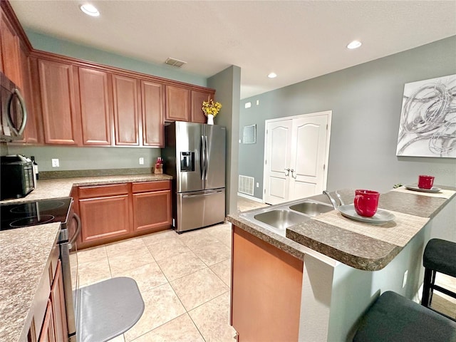 13303 Moss Park Ridge Dr, Orlando, FL 32832 - kitchen featuring stainless steel appliances, a kitchen bar, recessed lighting, brown cabinetry, and light tile patterned floors