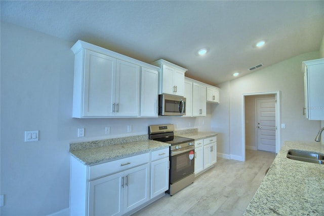 5427 Waterside Dr, Auburndale, FL 33823 - kitchen with appliances with stainless steel finishes, vaulted ceiling, recessed lighting, white cabinetry, and light stone countertops