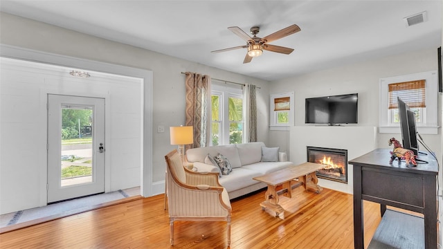 423 Ave H SE, Winter Haven, FL 33880 - living room with light wood-style flooring, a glass covered fireplace, healthy amount of natural light, and a ceiling fan