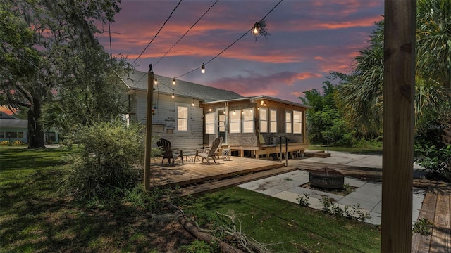 423 Ave H SE, Winter Haven, FL 33880 - back of house at dusk with a fire pit, a deck, and a lawn
