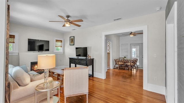 423 Ave H SE, Winter Haven, FL 33880 - living room featuring a ceiling fan, light wood-style flooring, and a glass covered fireplace