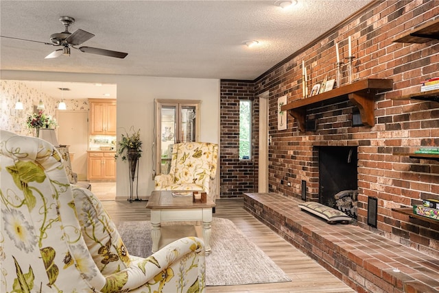 521 Lone Palm Dr, Lakeland, FL 33815 - living room featuring a textured ceiling, light wood-type flooring, ceiling fan, a brick fireplace, and brick wall