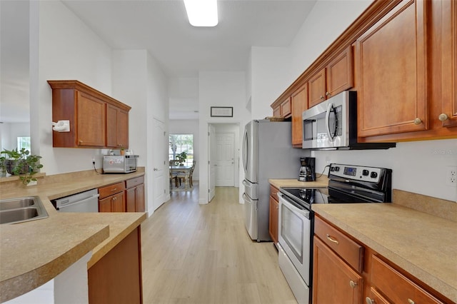 122 Amber Blvd, Auburndale, FL 33823 - kitchen with stainless steel appliances, light wood-style flooring, light countertops, and brown cabinets
