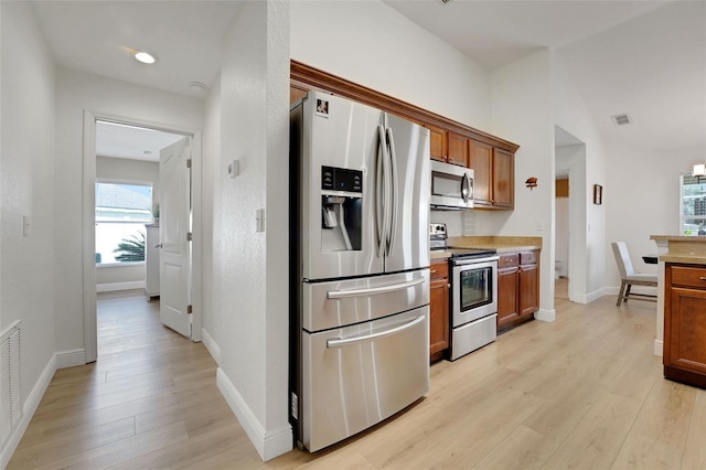 122 Amber Blvd, Auburndale, FL 33823 - kitchen with stainless steel appliances, light wood finished floors, brown cabinets, light countertops, and lofted ceiling