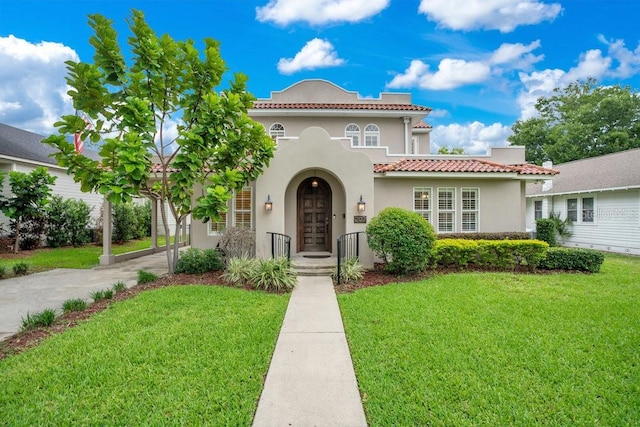 207 W Maxwell St, Lakeland, FL 33803 - mediterranean / spanish-style house with stucco siding, a front lawn, a tiled roof, and driveway