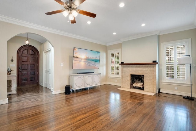 207 W Maxwell St, Lakeland, FL 33803 - living room featuring arched walkways, wood finished floors, a ceiling fan, a brick fireplace, and crown molding