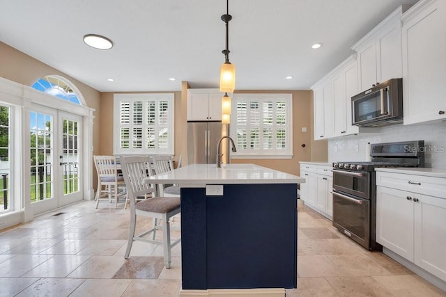 207 W Maxwell St, Lakeland, FL 33803 - kitchen featuring appliances with stainless steel finishes, backsplash, stone tile floors, a center island with sink, and white cabinets