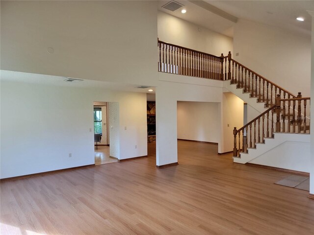 1842 Pinnacle Dr, Lakeland, FL 33813 - unfurnished living room featuring wood finished floors, stairs, a towering ceiling, and recessed lighting