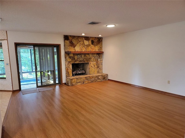 1842 Pinnacle Dr, Lakeland, FL 33813 - unfurnished living room with wood finished floors, a stone fireplace, and a textured ceiling