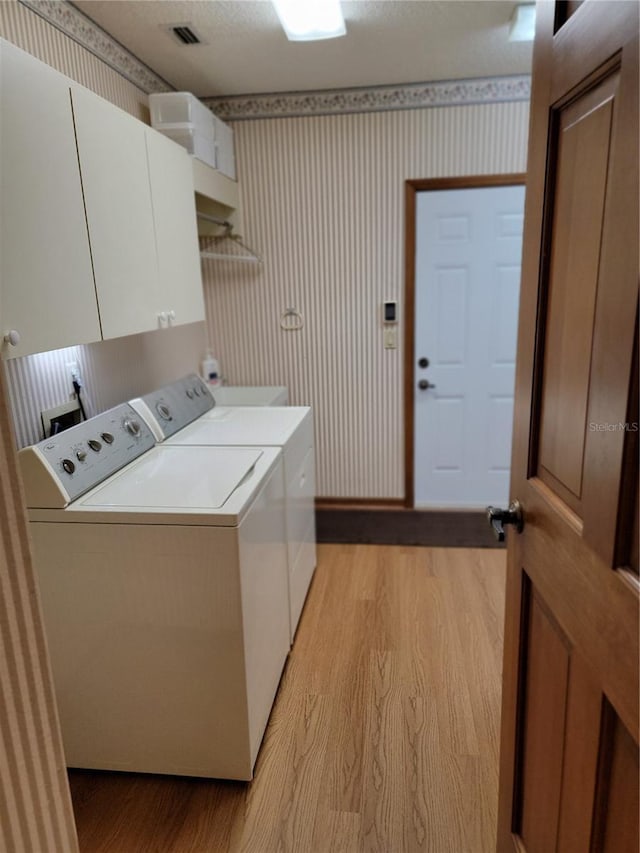 1842 Pinnacle Dr, Lakeland, FL 33813 - laundry area featuring washing machine and dryer, wallpapered walls, cabinet space, and light wood-style flooring