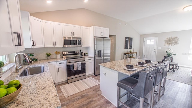 6262 NW 61st St, Ocala, FL 34482 - kitchen with appliances with stainless steel finishes, vaulted ceiling, a kitchen breakfast bar, light wood-style flooring, and white cabinets