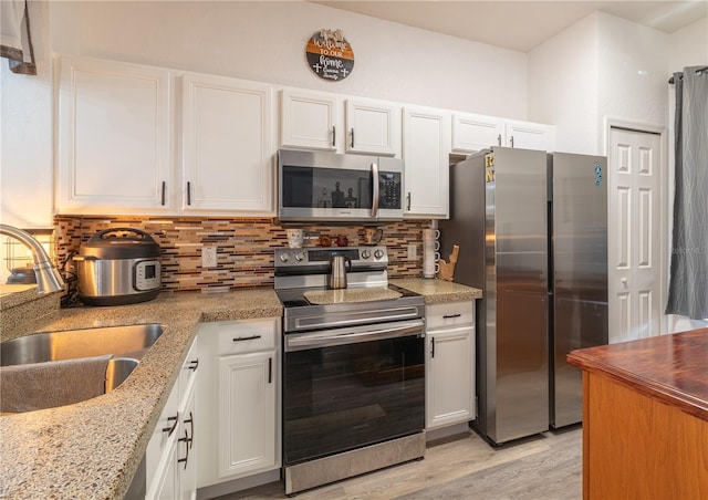 243 Palermo St, Davenport, FL 33897 - kitchen featuring stainless steel appliances, white cabinetry, light wood finished floors, and decorative backsplash