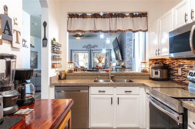 243 Palermo St, Davenport, FL 33897 - kitchen featuring appliances with stainless steel finishes, backsplash, white cabinetry, and a peninsula
