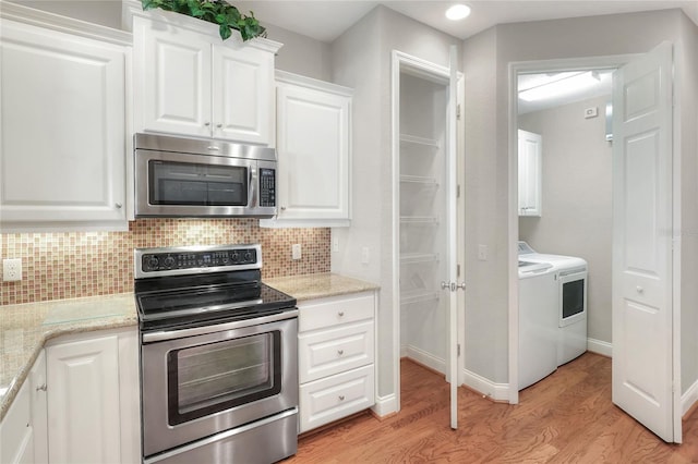 2929 Mission Lakes Dr Unit 10, Lakeland, FL 33803 - kitchen with stainless steel appliances, washer and dryer, light wood finished floors, backsplash, and white cabinets