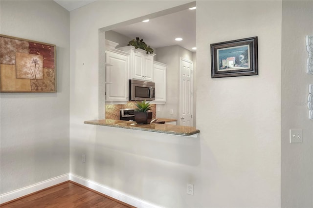 2929 Mission Lakes Dr Unit 10, Lakeland, FL 33803 - kitchen with stainless steel microwave, white cabinetry, wood finished floors, backsplash, and stove