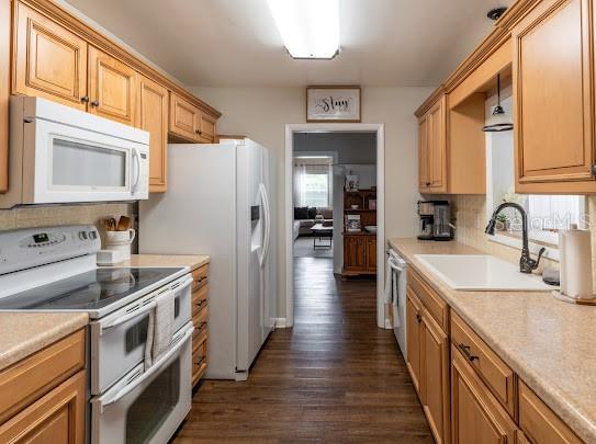 1420 S Lincoln Ave, Lakeland, FL 33803 - kitchen with white appliances, dark wood finished floors, light countertops, and backsplash
