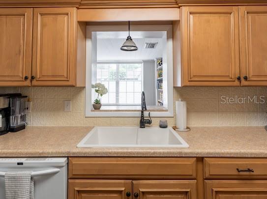 1420 S Lincoln Ave, Lakeland, FL 33803 - kitchen featuring white dishwasher, light countertops, backsplash, and pendant lighting