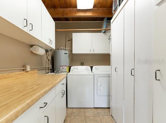 1420 S Lincoln Ave, Lakeland, FL 33803 - laundry area with electric water heater, independent washer and dryer, cabinet space, wood ceiling, and light tile patterned flooring