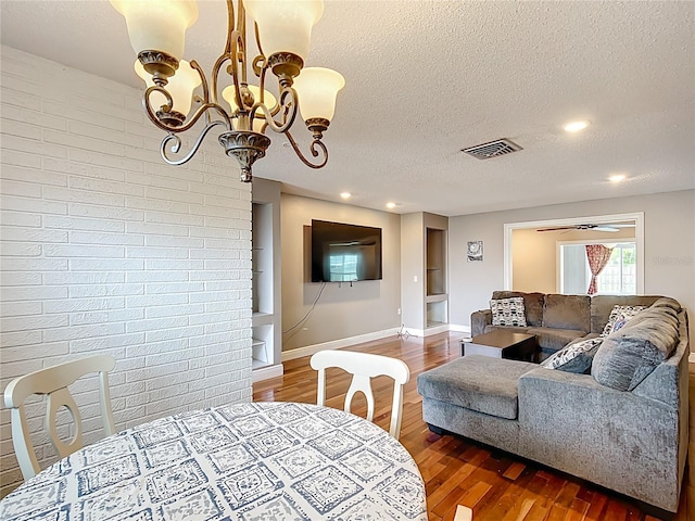 310 Keystone Rd, Auburndale, FL 33823 - dining room with a textured ceiling, wood finished floors, a chandelier, brick wall, and recessed lighting