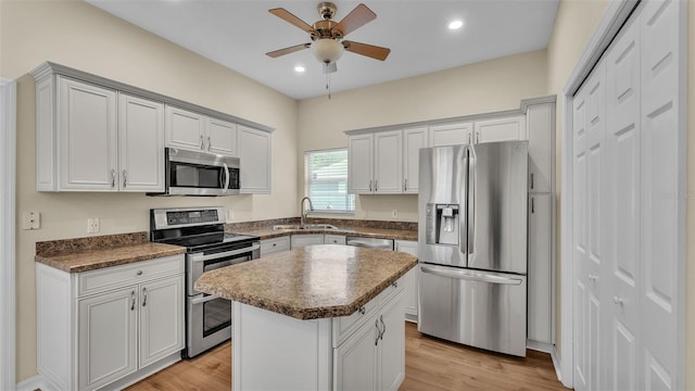 4445 Pebble Pointe Dr, Lakeland, FL 33813 - kitchen featuring stainless steel appliances, a ceiling fan, a kitchen island, dark countertops, and light wood-style flooring