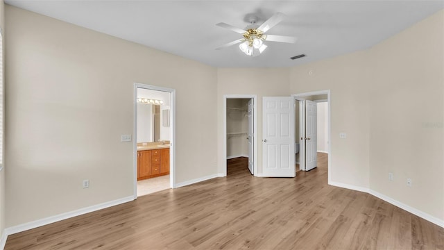 4445 Pebble Pointe Dr, Lakeland, FL 33813 - unfurnished bedroom featuring light wood-style flooring, a walk in closet, ensuite bathroom, and a ceiling fan