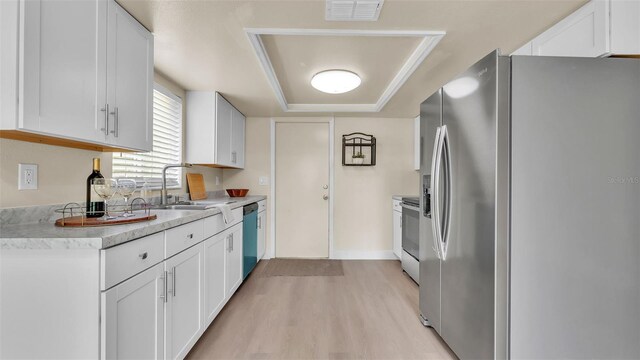 1100 Lowry Ave Unit 69, Lakeland, FL 33801 - kitchen with appliances with stainless steel finishes, a tray ceiling, light wood-type flooring, light countertops, and white cabinets