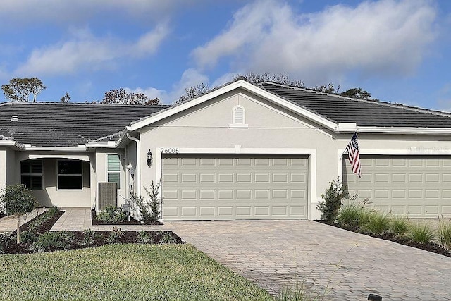 26005 Bimini Sands Ct, Englewood, FL 34223 - ranch-style home with stucco siding, decorative driveway, a garage, and a tiled roof