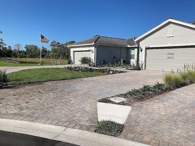 26005 Bimini Sands Ct, Englewood, FL 34223 - ranch-style house featuring decorative driveway, a garage, stucco siding, a tile roof, and a front lawn