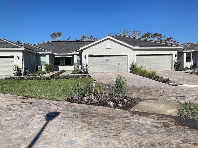 26005 Bimini Sands Ct, Englewood, FL 34223 - ranch-style house with stucco siding, decorative driveway, an attached garage, and a front lawn