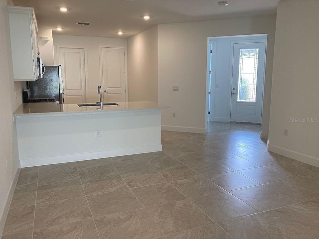 26005 Bimini Sands Ct, Englewood, FL 34223 - kitchen with a peninsula, white cabinetry, stainless steel microwave, recessed lighting, and freestanding refrigerator