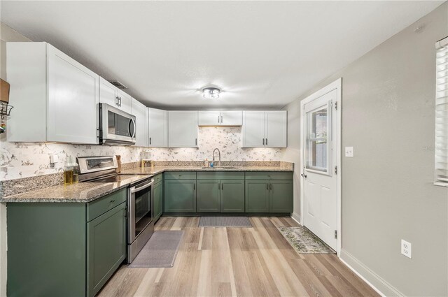 1231 Melville Ave, Lakeland, FL 33805 - kitchen featuring green cabinets, stainless steel appliances, light wood-style floors, white cabinetry, and tasteful backsplash