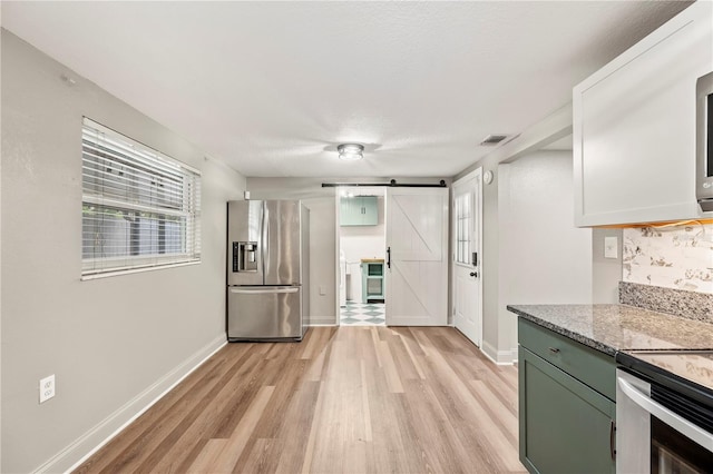 1231 Melville Ave, Lakeland, FL 33805 - kitchen with appliances with stainless steel finishes, a barn door, light wood-type flooring, light stone countertops, and green cabinetry