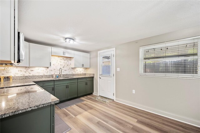 1231 Melville Ave, Lakeland, FL 33805 - kitchen with light wood-type flooring, white cabinets, decorative backsplash, and stone countertops