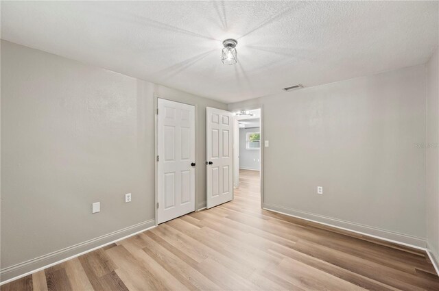 1231 Melville Ave, Lakeland, FL 33805 - unfurnished bedroom featuring light wood-type flooring and a textured ceiling
