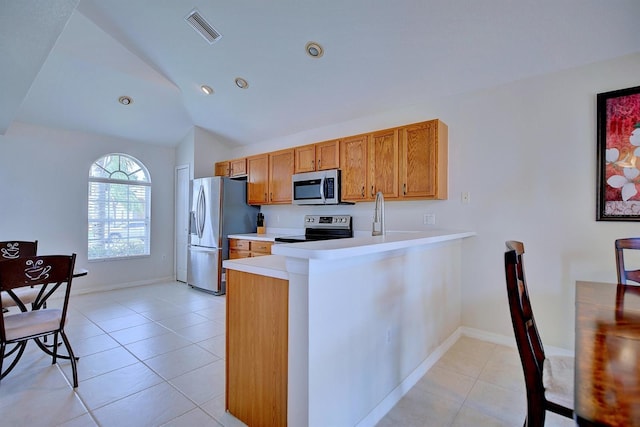 3782 Rollingsford Cir, Lakeland, FL 33810 - kitchen featuring appliances with stainless steel finishes, vaulted ceiling, light tile patterned floors, brown cabinets, and light countertops