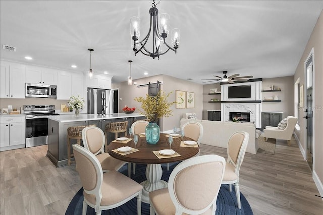 3063 Lantana Cir, Auburndale, FL 33823 - dining room featuring a ceiling fan, a barn door, recessed lighting, a glass covered fireplace, and a chandelier