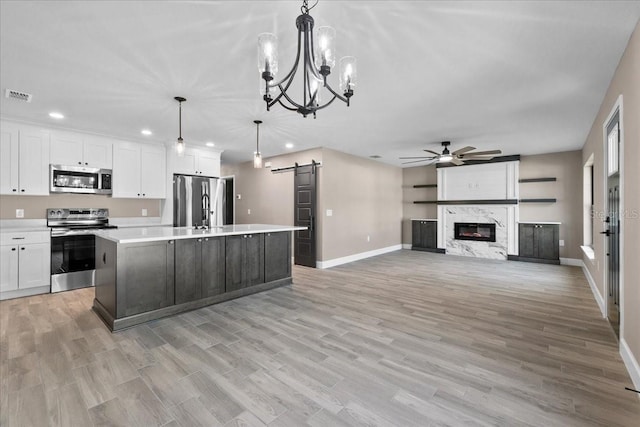 3063 Lantana Cir, Auburndale, FL 33823 - kitchen with stainless steel appliances, a barn door, a ceiling fan, light countertops, and white cabinets
