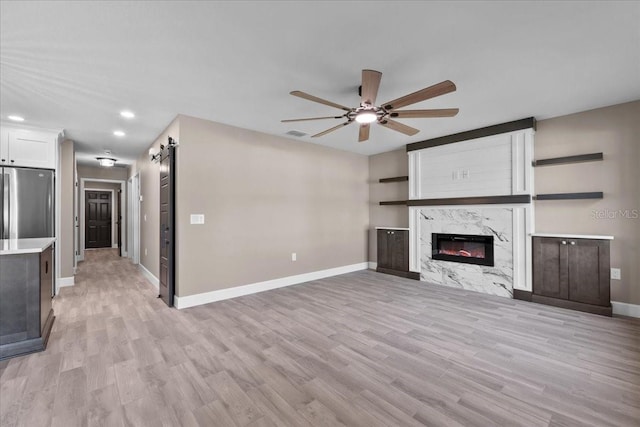 3063 Lantana Cir, Auburndale, FL 33823 - unfurnished living room with a ceiling fan, light wood-type flooring, recessed lighting, and a high end fireplace