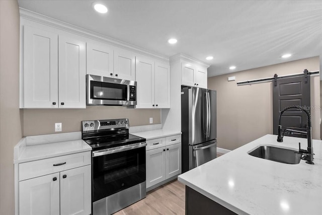 3063 Lantana Cir, Auburndale, FL 33823 - kitchen with stainless steel appliances, a barn door, white cabinets, recessed lighting, and light wood-style floors