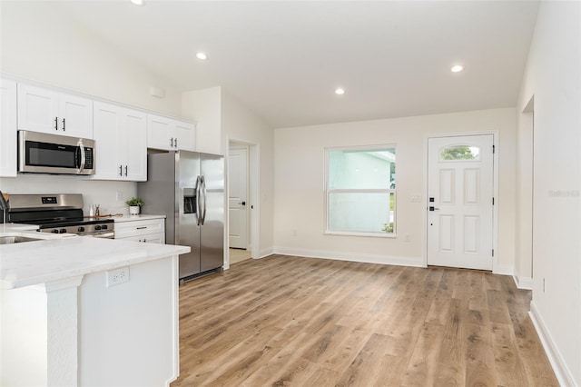 724 Voight Ave N, Fort Meade, FL 33841 - kitchen featuring stainless steel appliances, white cabinets, light wood-style floors, light stone countertops, and lofted ceiling