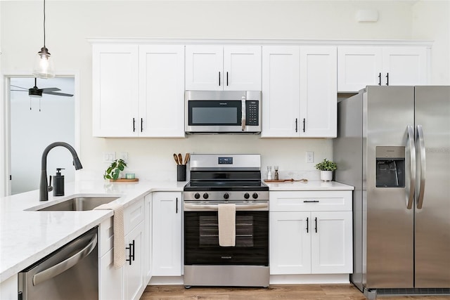 724 Voight Ave N, Fort Meade, FL 33841 - kitchen featuring stainless steel appliances, white cabinetry, light wood-style flooring, a ceiling fan, and decorative light fixtures