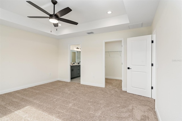724 Voight Ave N, Fort Meade, FL 33841 - unfurnished bedroom with light carpet, a raised ceiling, a spacious closet, recessed lighting, and connected bathroom