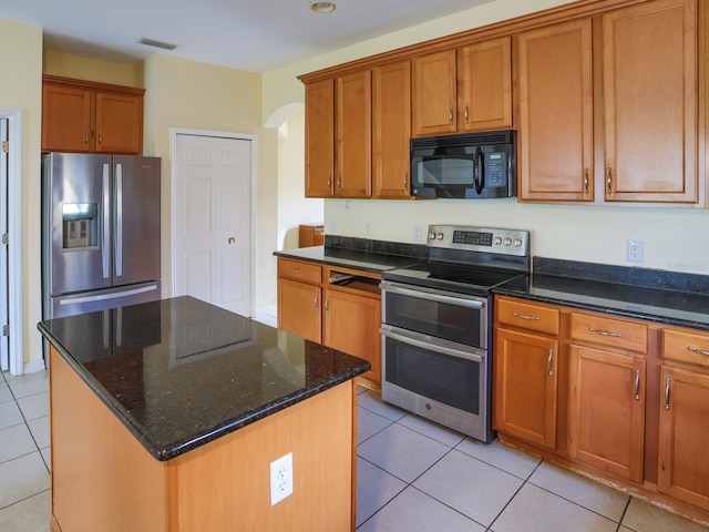 1911 Wind Meadows Dr, Bartow, FL 33830 - kitchen with appliances with stainless steel finishes, arched walkways, brown cabinetry, and light tile patterned flooring