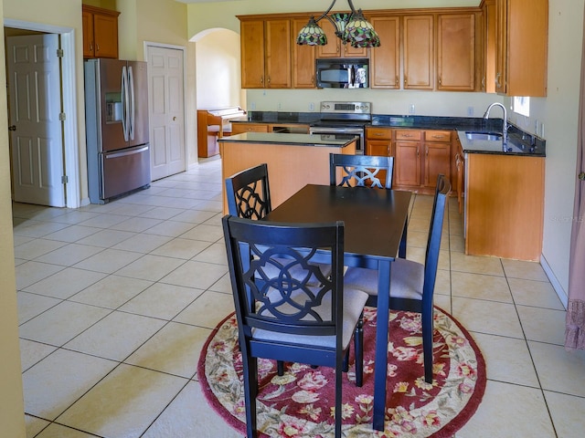 1911 Wind Meadows Dr, Bartow, FL 33830 - kitchen with appliances with stainless steel finishes, arched walkways, light tile patterned flooring, brown cabinets, and dark countertops