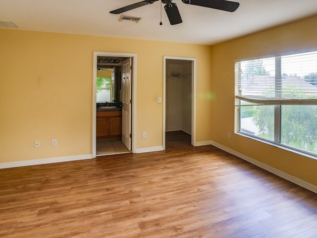 1911 Wind Meadows Dr, Bartow, FL 33830 - unfurnished bedroom with light wood-style flooring, a walk in closet, ensuite bathroom, and ceiling fan
