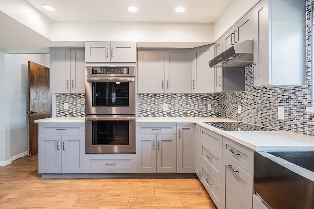 252 W Brookins Ave, Eagle Lake, FL 33839 - kitchen featuring double oven, black electric cooktop, under cabinet range hood, gray cabinetry, and light countertops