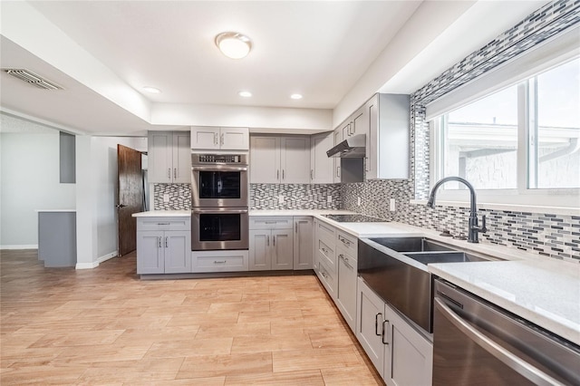 252 W Brookins Ave, Eagle Lake, FL 33839 - kitchen featuring gray cabinetry, appliances with stainless steel finishes, under cabinet range hood, tasteful backsplash, and recessed lighting