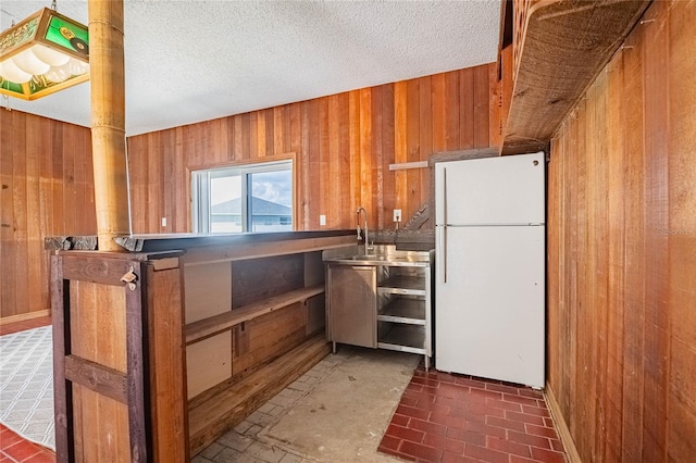 252 W Brookins Ave, Eagle Lake, FL 33839 - kitchen with freestanding refrigerator, wood walls, brown cabinetry, and brick patterned flooring