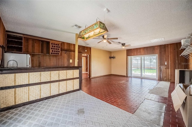 252 W Brookins Ave, Eagle Lake, FL 33839 - unfurnished living room featuring wood walls, ceiling fan, a textured ceiling, and brick patterned floors